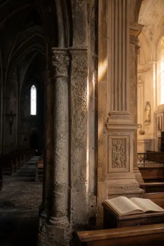 Textured stone pillar inside a Haute-Marne church, contrasting Gothic arches and Renaissance details in warm afternoon light.
